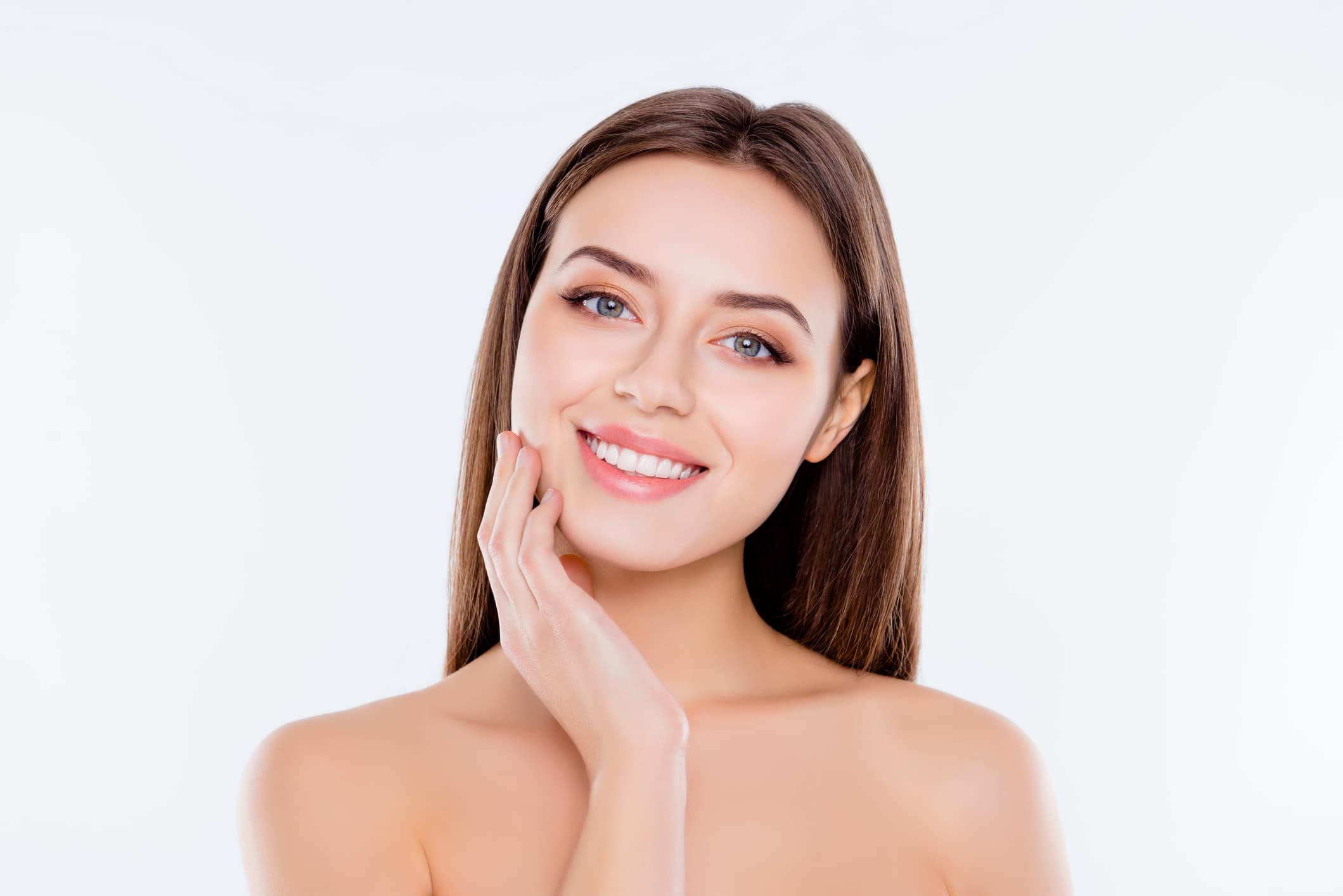 A woman smiling and touching her cheek after exosome therapy in Coral Gables